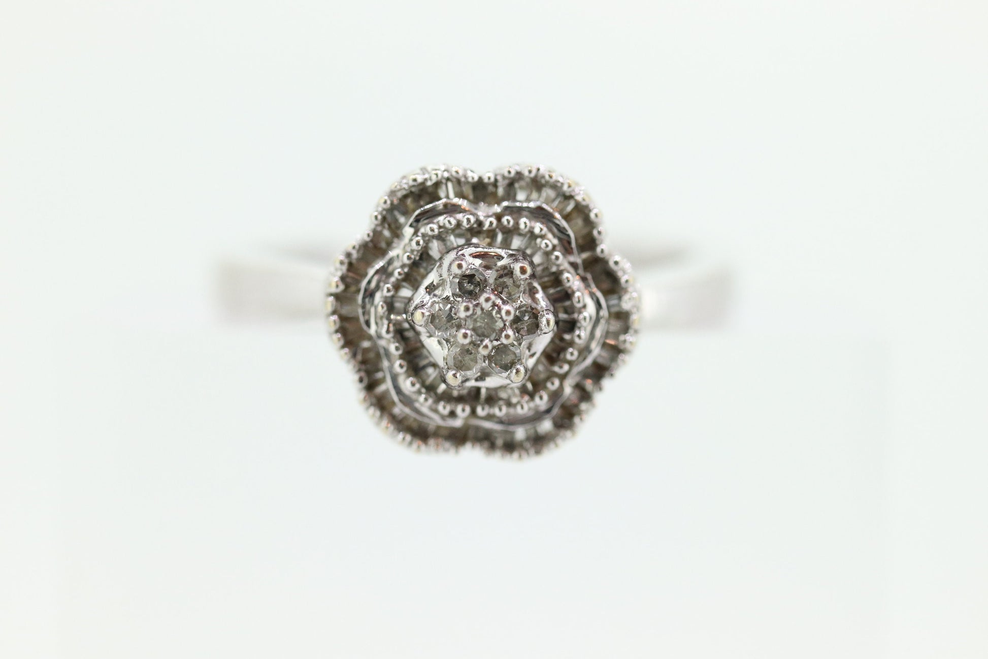 Diamond Daisy Cluster Elevated Ring. 10k White gold with round baguette diamond flower arrangement. st(52/90)