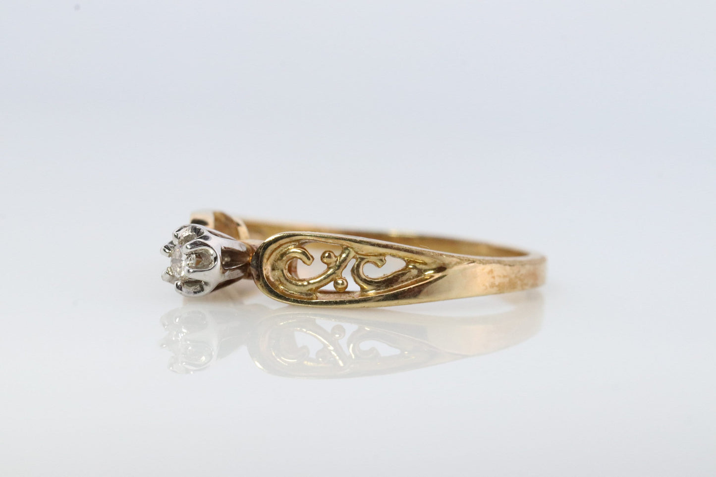 10k Diamond Solitaire. 10k Yellow gold engraved illusion set diamond ring. Filigree shank.